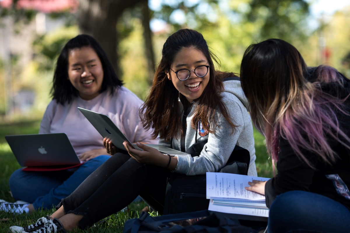 three students doing homework outside